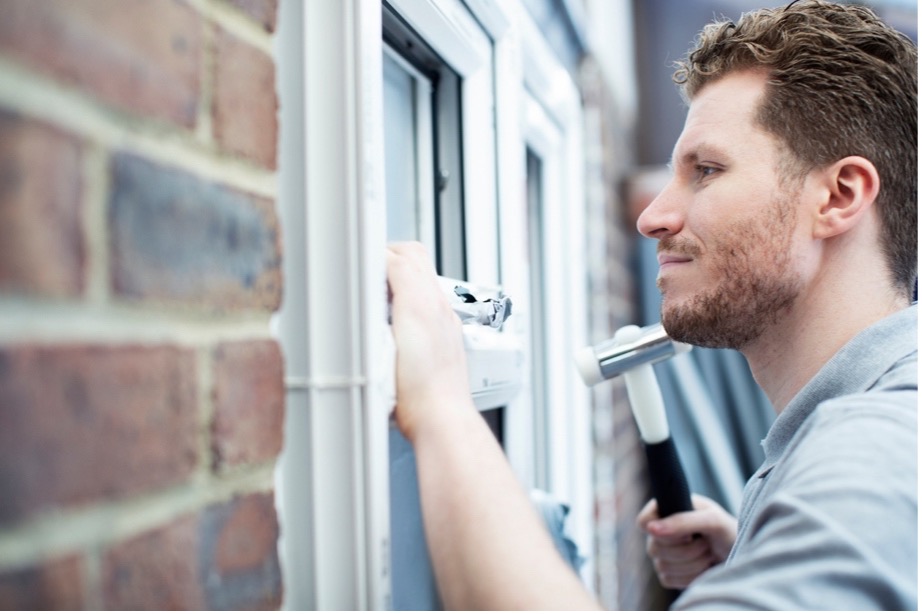 A person using a hammer to remove a window